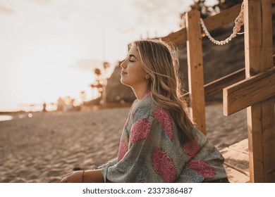 Portrait of one young woman at the beach with closed eyes enjoying free time and freedom outdoors. Having fun relaxing and living happy moments.