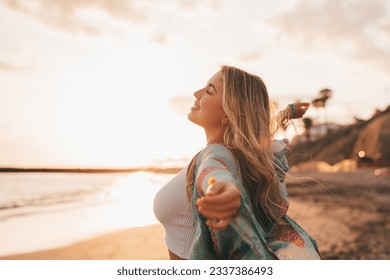 Portrait of one young woman at the beach with openened arms enjoying free time and freedom outdoors. Having fun relaxing and living happy moments.
