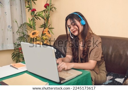 Portrait of an online worker. Using her laptop and headset as tools of communication to connect to other people.