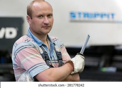 Portrait operator man worker at factory equipment background with deburring tool in hand for removing steel burrs from metal sheet or workpiece after a modification process  - Powered by Shutterstock