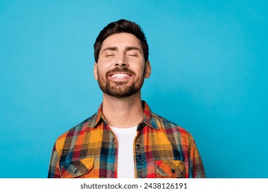 Portrait of optimistic dreamy positive guy with stubble wear plaid shirt smiling close eyes relaxing isolated on blue color background - Powered by Shutterstock