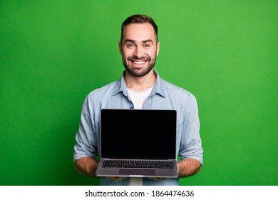 Portrait of optimistic funky guy show laptop wear blue shirt isolated on vibrant green color background - Powered by Shutterstock