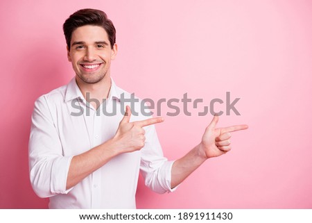 Portrait of optimistic funny guy point empty space wear white shirt isolated on pink color background