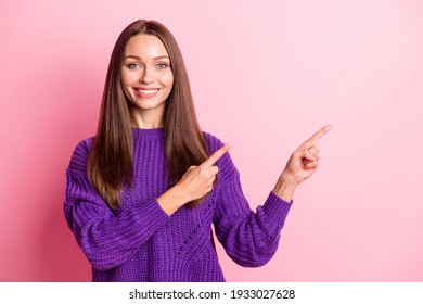 Portrait of optimistic girl point empty space wear lilac sweater isolated on pastel pink color background