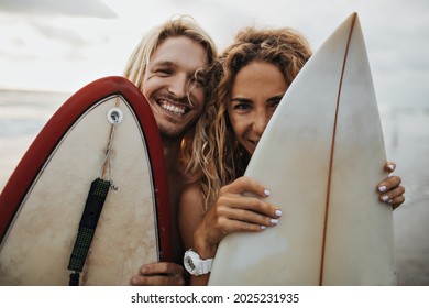 Portrait of optimistic guy and girl hiding behind surfboards - Powered by Shutterstock