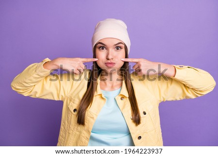 Portrait of optimistic straight hairdo girl puff cheeks wear cap jacket isolated on purple color background