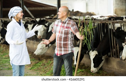 Portrait Of Ordinary Worker And Doctor Working In Cowhouse
