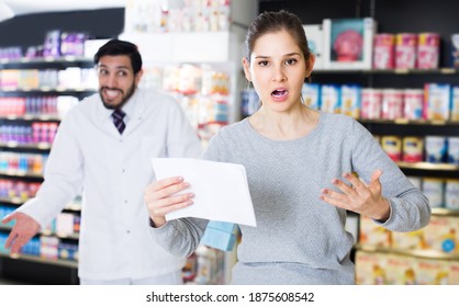 Portrait Of Outraged Female Customer With Medicines In Pharmacy