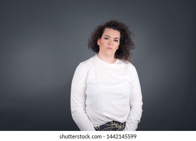 Portrait of outraged young hispanic woman with oval face and curly hair wearing White  sweater frowning her eyebrows being displeased with something. Scowling pretty female isolated over grey. - Shutterstock ID 1442145599