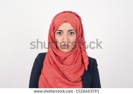 Portrait of outraged young muslim woman with oval face, frowning her eyebrows being displeased with something. Scowling pretty female isolated over white