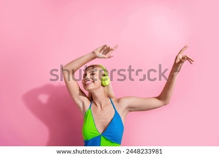 Portrait of overjoyed cute woman with bob hair wear colorful top listen music in headphones hands up isolated on pink color background
