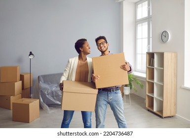 Portrait of overjoyed ethnic couple celebrate moving relocating to new house together. Smiling biracial man and woman young family with boxes on relocation day. Home ownership. Real estate concept.