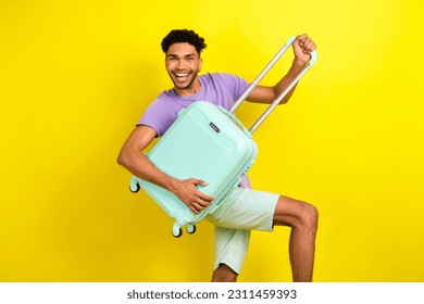 Portrait of overjoyed handsome young person beaming smile arms hold suitcase isolated on yellow color background - Shutterstock ID 2311459393