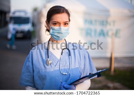 Portrait of overworked stressed worried NHS UK ICU doctor in front of EMS hospital,Emergency Medical Services frontliner,COVID-19 pandemic outbreak crisis,key worker medical staff working long shifts  Foto stock © 