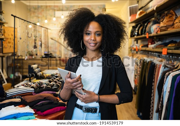 Portrait of the owner of\
a clothing store at the entrance of the new business with the\
tablet in hand to analyze the sales, new orders to be sent and\
check the stocks