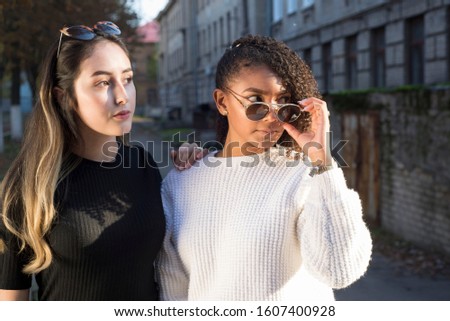 Portrait of a pair of beautiful Hispanic girls in sunglasses. Against the background of an old building. Fashion shot
