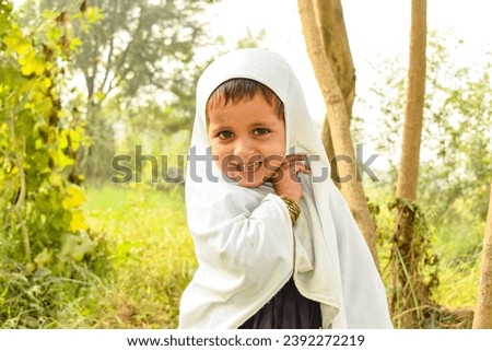 Portrait of a Pakistani baby girl wearing hijab. Asian Baby girl wearing White hijab and posing beautifully against farms. Beautiful Asian Pakistani kid. Pakistani kid. Islamic baby girl. Islamic baby