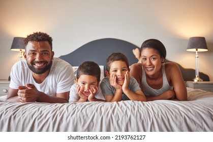 Portrait Of Parents And Kids Lying On Bed In The Morning With A Smile. Playful, Fun, Mom And Dad Playing Indoors Showing Growth, Child Development, Happiness And Childhood Innocence From Little Boys