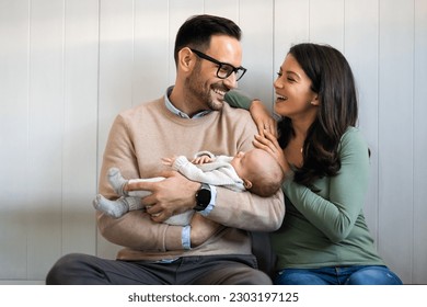 Portrait of parents and newborn baby. Father and mother kiss and hug a beautiful newborn child. . - Powered by Shutterstock