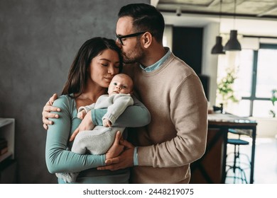 Portrait of parents and newborn baby. Father and mother kiss and hug a beautiful newborn child. . - Powered by Shutterstock