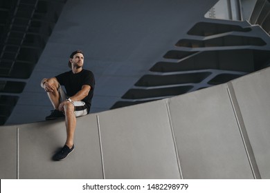 Portrait Of Parkour Athlete Sitting On Edge Of The Wall After Hard Freerunning