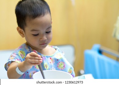 Portrait Of Patient Kid  Sit On Patient Bed With Food Tray In Front Of Him Little Boy Looks Sick,tired, Bad Mood,ill,sleepy And  No Appetite.