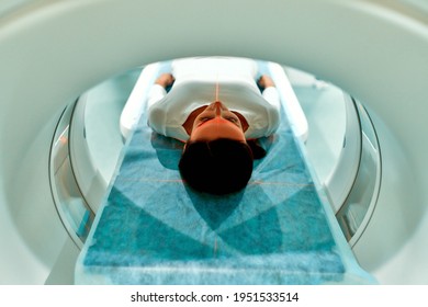 Portrait of a patient lying on CT or MRI, the bed moves inside the machine, scanning her body and brain. In a medical laboratory with high-tech equipment.