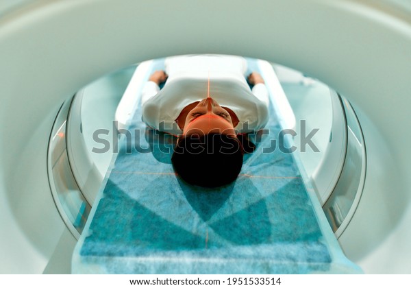 Portrait of a patient lying on CT or MRI, the\
bed moves inside the machine, scanning her body and brain. In a\
medical laboratory with high-tech\
equipment.