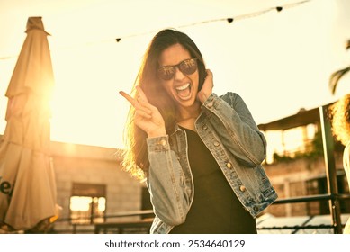 Portrait, peace sign and happy woman with sunglasses in city at sunset outdoor. Face, excited and girl with v hand gesture on rooftop for cool fashion, funny emoji and laughing on holiday in Brazil - Powered by Shutterstock