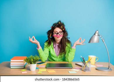 Portrait Of Peaceful Girl Sit Table Meditate Have Messy Pencil Hairstyle Isolated Over Blue Color Background