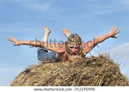 portrait of peasant in a field on a haystack in summer day