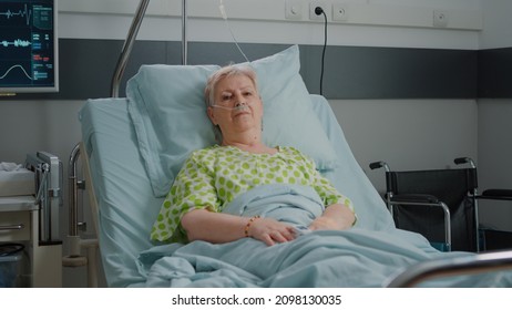 Portrait of pensioner waiting to receive medical support in hospital ward, laying in bed with nasal oxygen tube and IV drip bag. Aged patient preparing to cure sickness. Healthcare service - Shutterstock ID 2098130035
