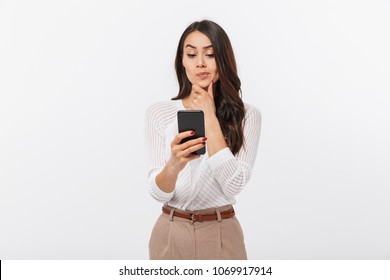 Portrait Of A Pensive Asian Businesswoman Using Mobile Phone Isolated Over White Background