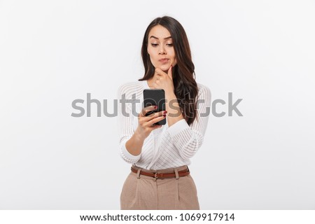 Portrait of a pensive asian businesswoman using mobile phone isolated over white background