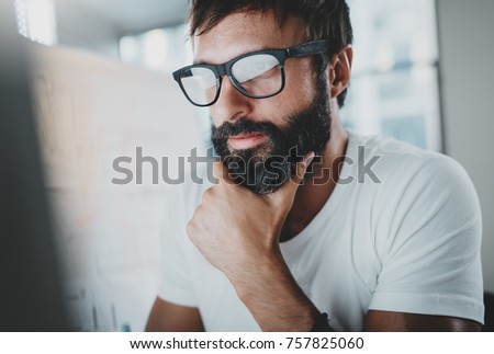 Portrait of pensive bearded designer working at the modern office loft.Horizontal. Blurred background