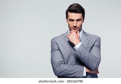 Portrait of a pensive businessman touching his chin over gray background