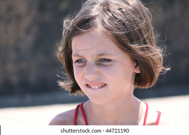 Portrait Of A Pensive Child Biting Her Lip Outdoors