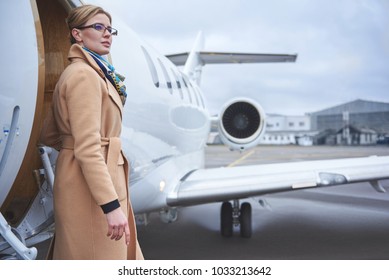 Portrait Of Pensive Female Standing Near Private Airplane. Wealth And Career Concept