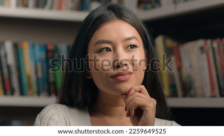 Portrait pensive korean woman standing in library near bookshelf think ponder deep in thought in search solution happy female comes up with good idea remembers make gesture raises finger finds answer