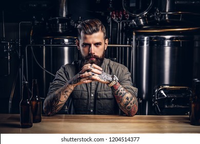 Portrait of a pensive tattooed hipster male with stylish beard and hair in the shirt in indie brewery.   - Powered by Shutterstock