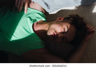 Portrait Of Pensive Young Handsome Chinese Man Lying On Floor And Looking Away 