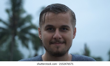 Portrait Of Pensive Young Man Standing In The Pouring Rain And Getting Soaked While Looking Into The Sky. Slow Motion