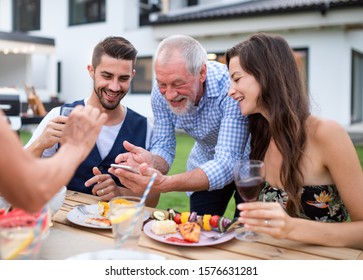 Portrait of people outdoors on family garden barbecue, taking selfie. - Powered by Shutterstock