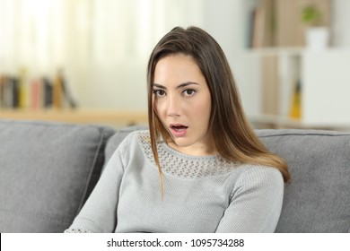 Portrait Of A Perplexed Woman Looking At Camera Sitting On A Couch In The Living Room At Home. She Does Not Believe You