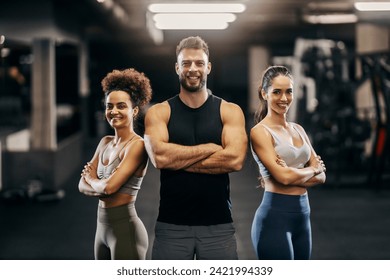 Portrait of a personal trainer with sportswomen posing in a gym with arms crossed and smiling at the camera. - Powered by Shutterstock