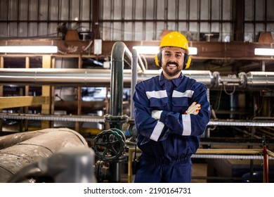 Portrait Of Petrochemical Refinery Worker Wearing Earmuff Due To Noisy Environment In Factory.