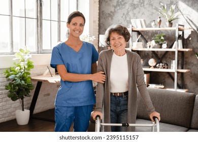 Portrait pf happy smiling caretaker medicine worker nurse helping elderly senior old patient with walking frame. Rehabilitation after trauma injury - Shutterstock ID 2395115157