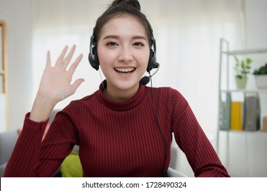 Portrait Photo Of Asian Woman Using Video Call Communicate With Business Colleague Friend From Home During Self Isolation From Coronavirus Outbreak Crisis. Asian Woman Waving Hand Looking At Camera.