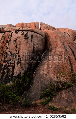 Portrait photo of a big rock at sunrise with blue cloudy sky in the background shot from the bottom. Shot in Kruger National Park, South Africa. 