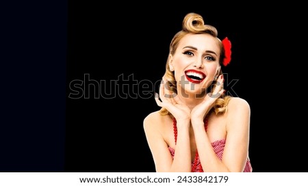Portrait photo of excited surprised, very happy beautiful blonde woman. Pinup girl with open mouth and raised hands showing toothy smile. Retro vintage concept. Dark black background.